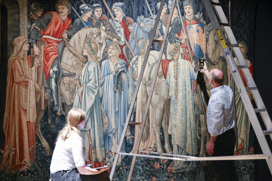 Light levels are checked during the installation of The Legend of King Arthur exhibition. Two Tullie staff stand in front of one of the huge Edward Burne-Jones and William Morris tapestries.